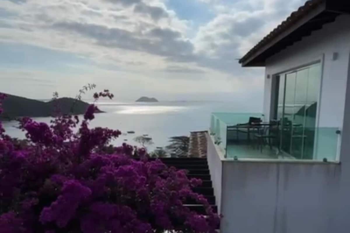 A modern building with a glass balcony overlooking a coastal view.