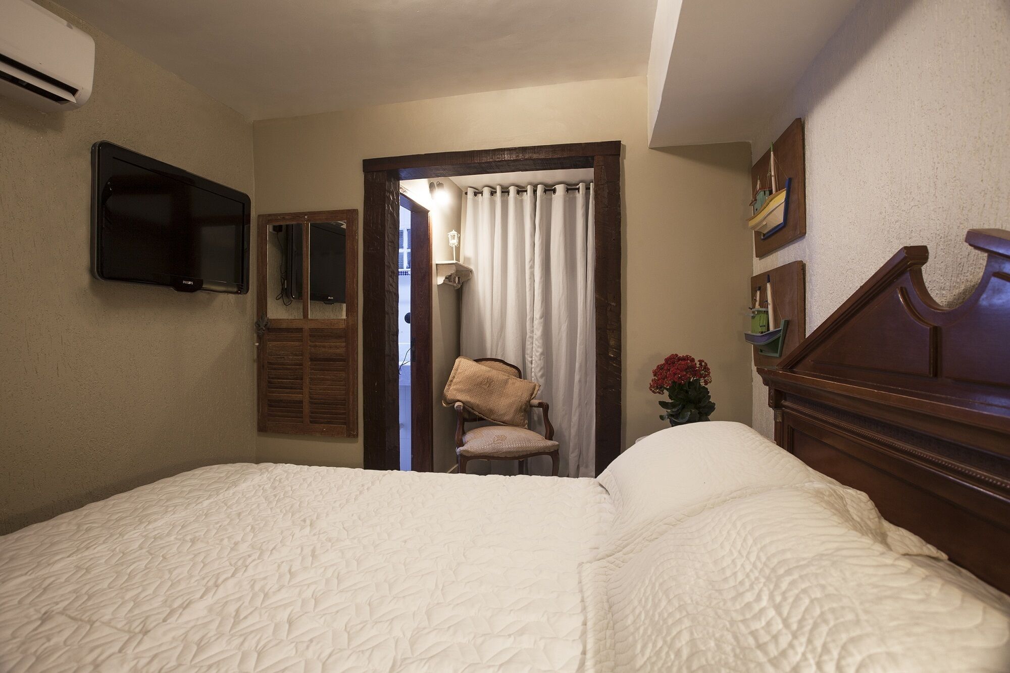 A hotel room with a bed, a chair, a TV, and a window with curtains.