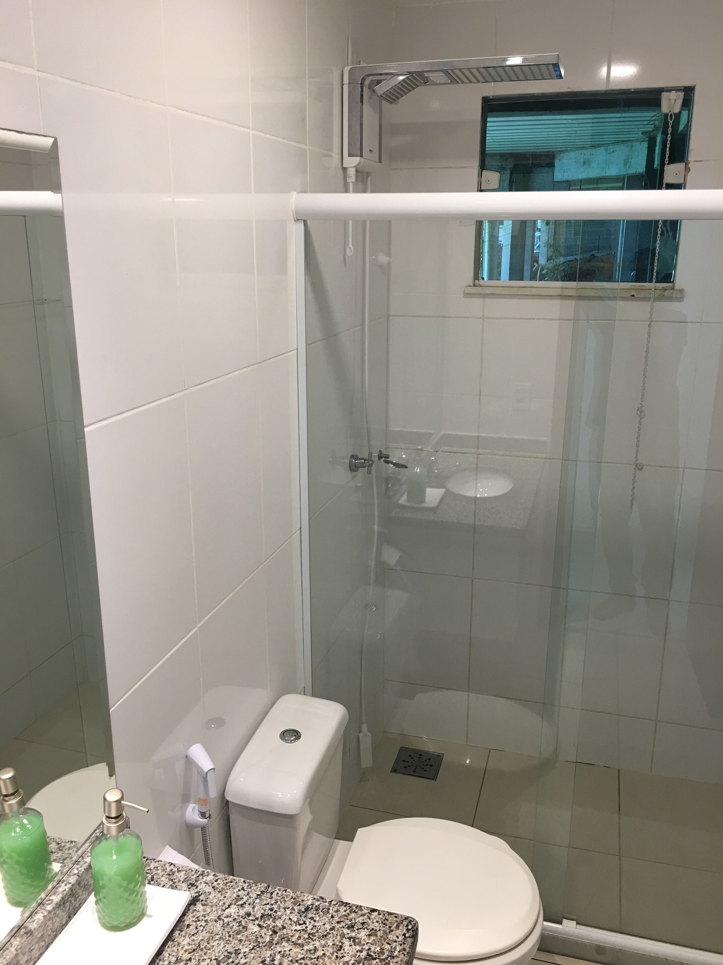 Ein Badezimmer mit einer Duschkabine, einer Toilette und einem Waschbecken mit Granitplatte.