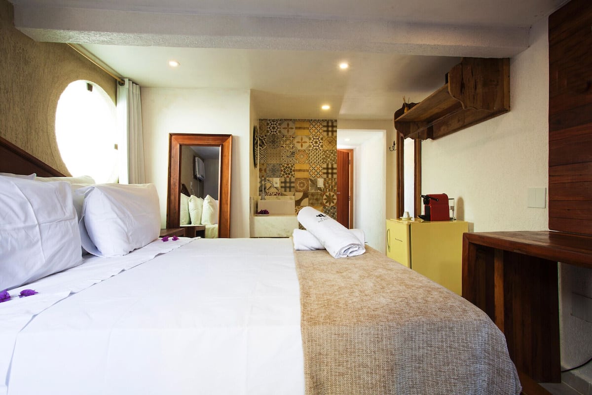 A hotel room with a bed, a bathroom, and a wooden cabinet.