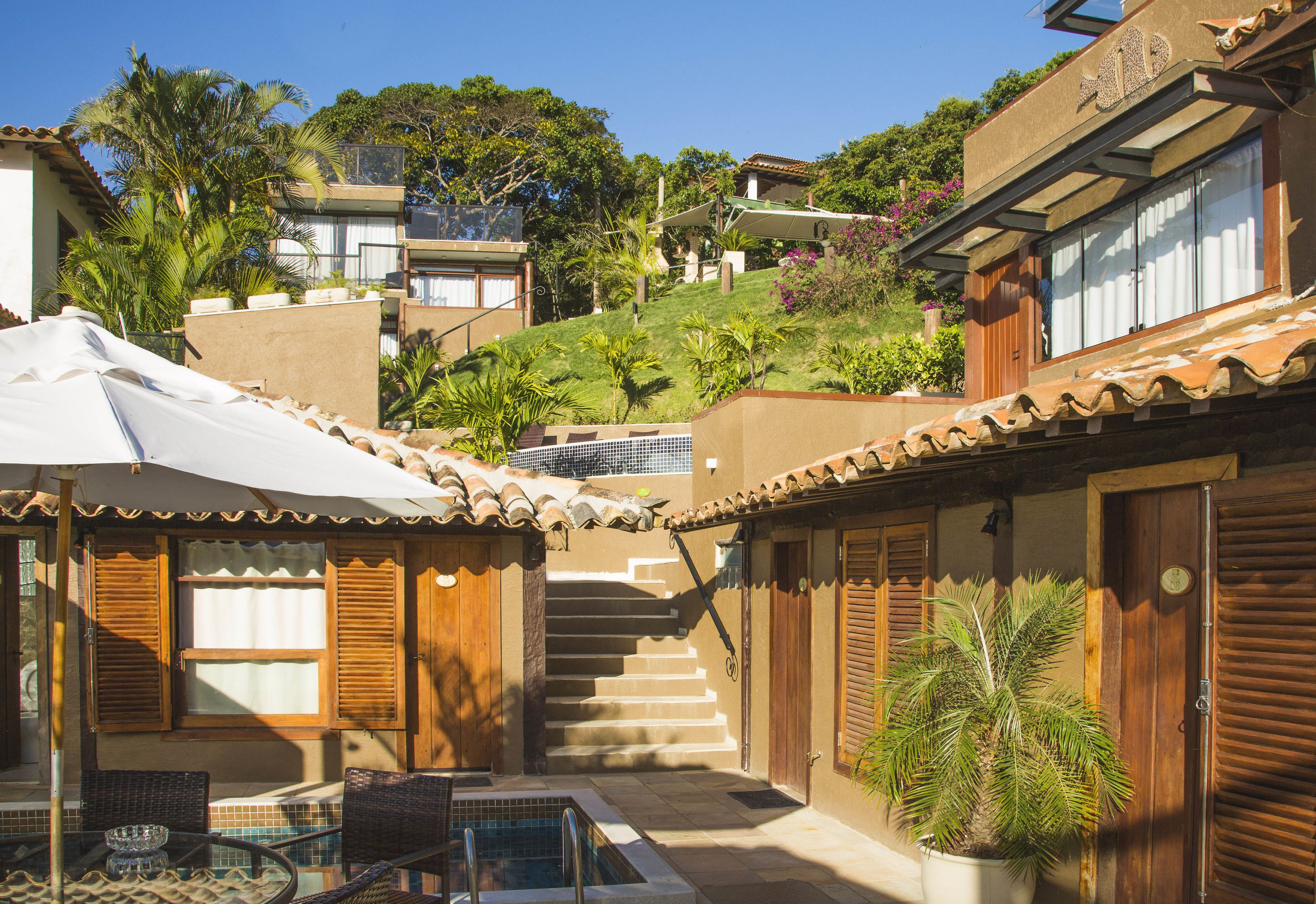 A courtyard with a pool, outdoor seating, and a staircase leading to a building.