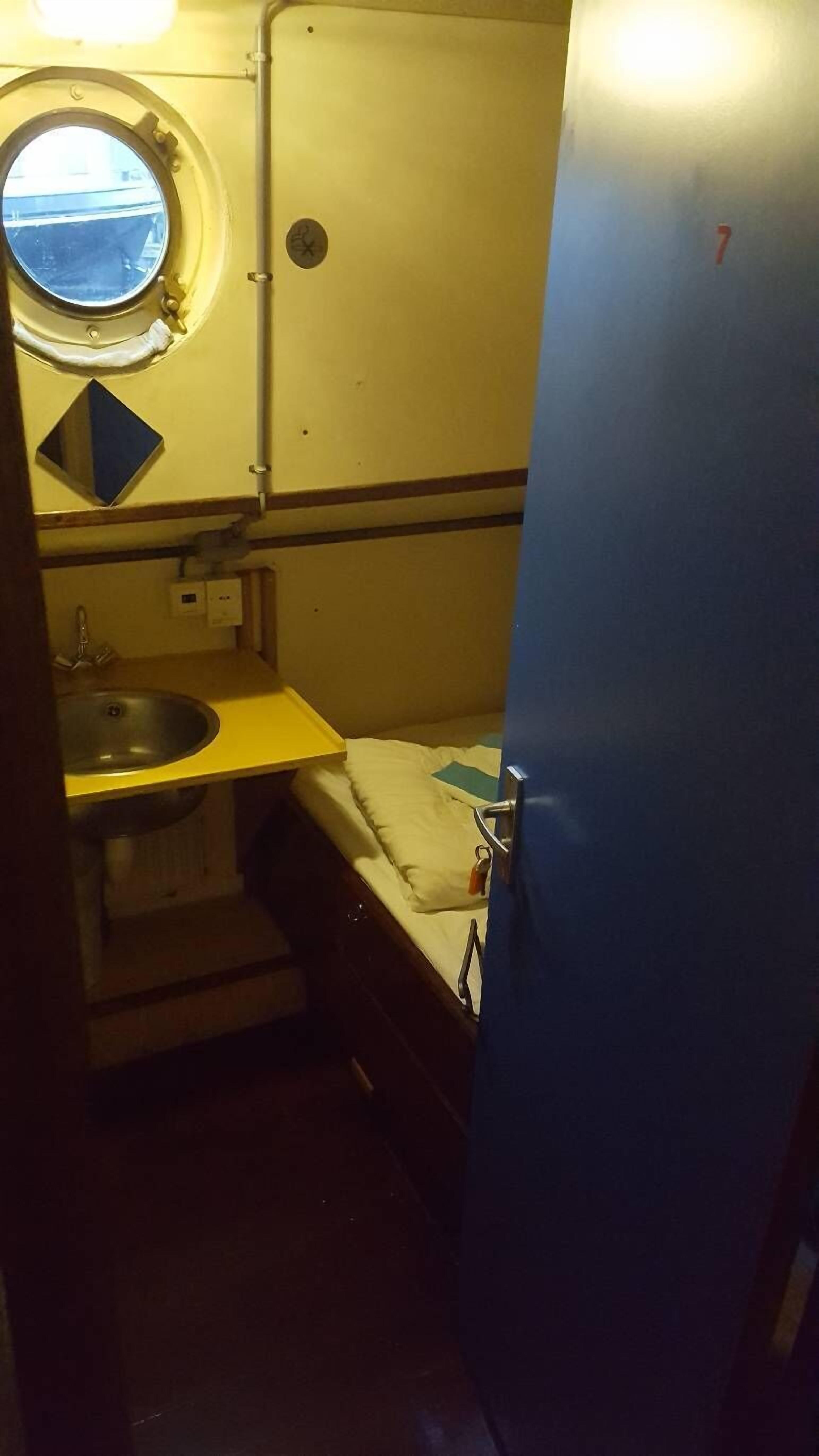 A small, compact bathroom with a sink, a mirror, and a window.
