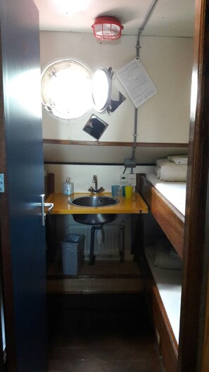 Una kitchenette compacta con un lavamanos, un espejo y una pequeña encimera.