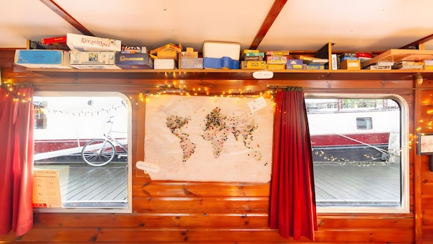 Une cabane aux murs en bois, une carte du monde accrochée au mur et un vélo à l’extérieur.