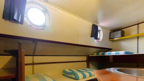Une chambre avec un lit superposé, une fenêtre, un lavabo et une étagère.