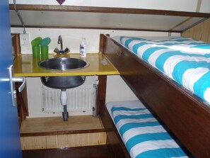 Una cama litera con una pequeña zona de kitchenette que incluye un lavamanos, un grifo y un dispensador de jabón.