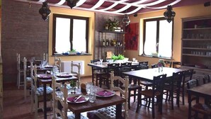 A dining area with multiple tables and chairs, a brick wall, and a ceiling with draped fabric. - Bio Agriturismo Valle dei Calanchi (Castiglione in Teverina)