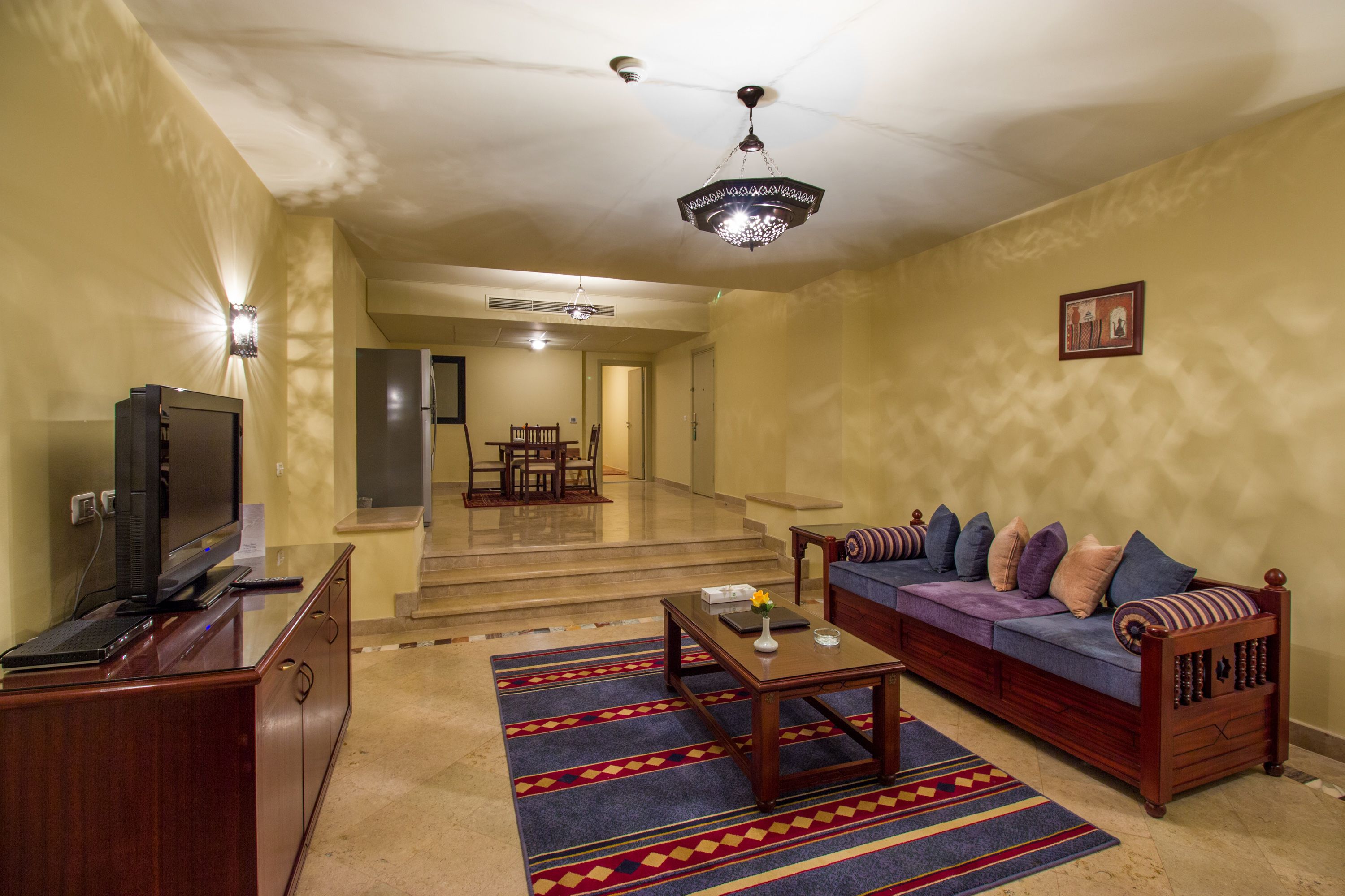 A living room with a sofa, coffee table, and television. There is a staircase leading to another room.