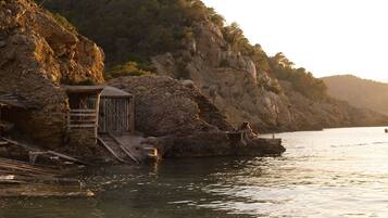 Di pantai, pasir putih, kursi berjemur, dan payung pantai