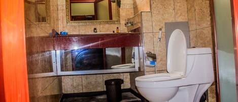 A bathroom with a toilet, sink, mirror, and tiled walls.
