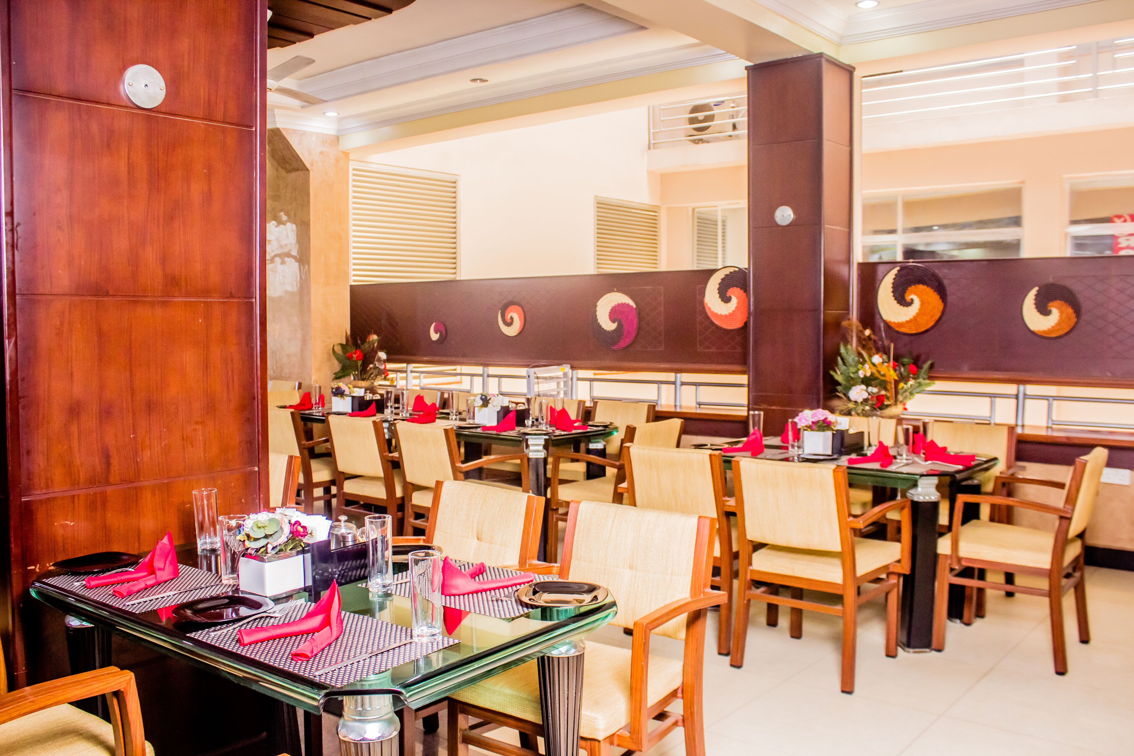 A restaurant with multiple tables set with red napkins, glasses, and cutlery.