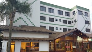 A hotel with a tiled facade, a covered entrance, and a palm tree in front.
