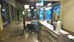 A reception area with a counter, chairs, and a potted plant.