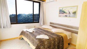 A bedroom with a large window, a bed with a leopard print bedspread, and a painting on the wall.