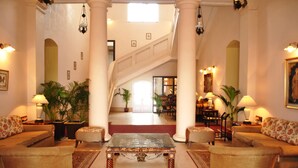 A spacious lobby with a grand staircase, comfortable seating, and decorative lighting. - Mahodadhi Palace (Puri)