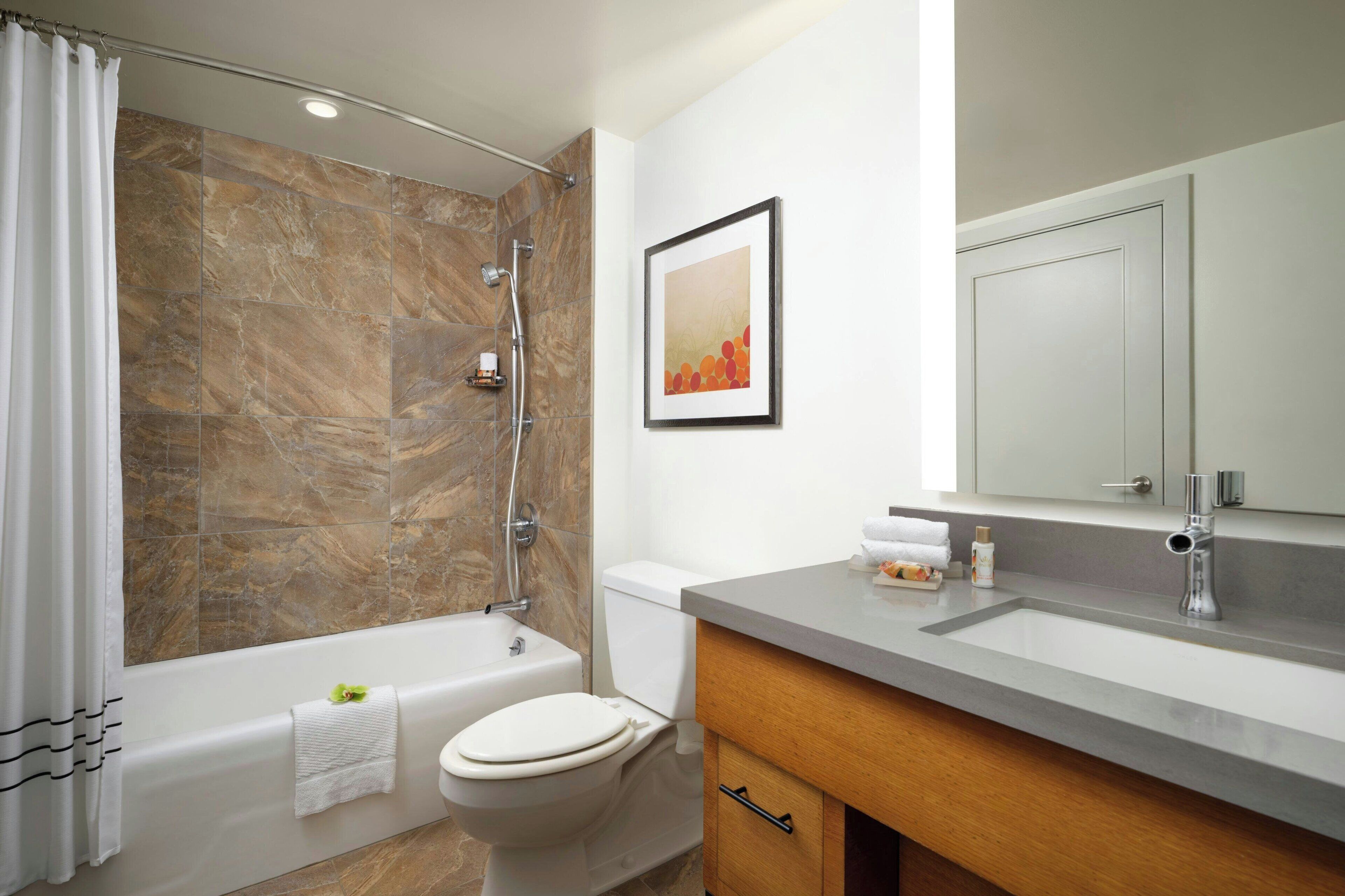 A modern bathroom with a bathtub, toilet, and shower.