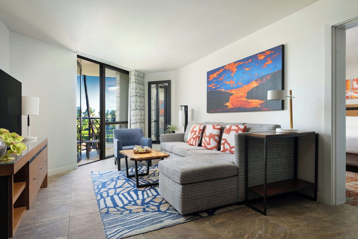 A modern living room with a grey sofa, a coffee table, and a large painting on the wall.