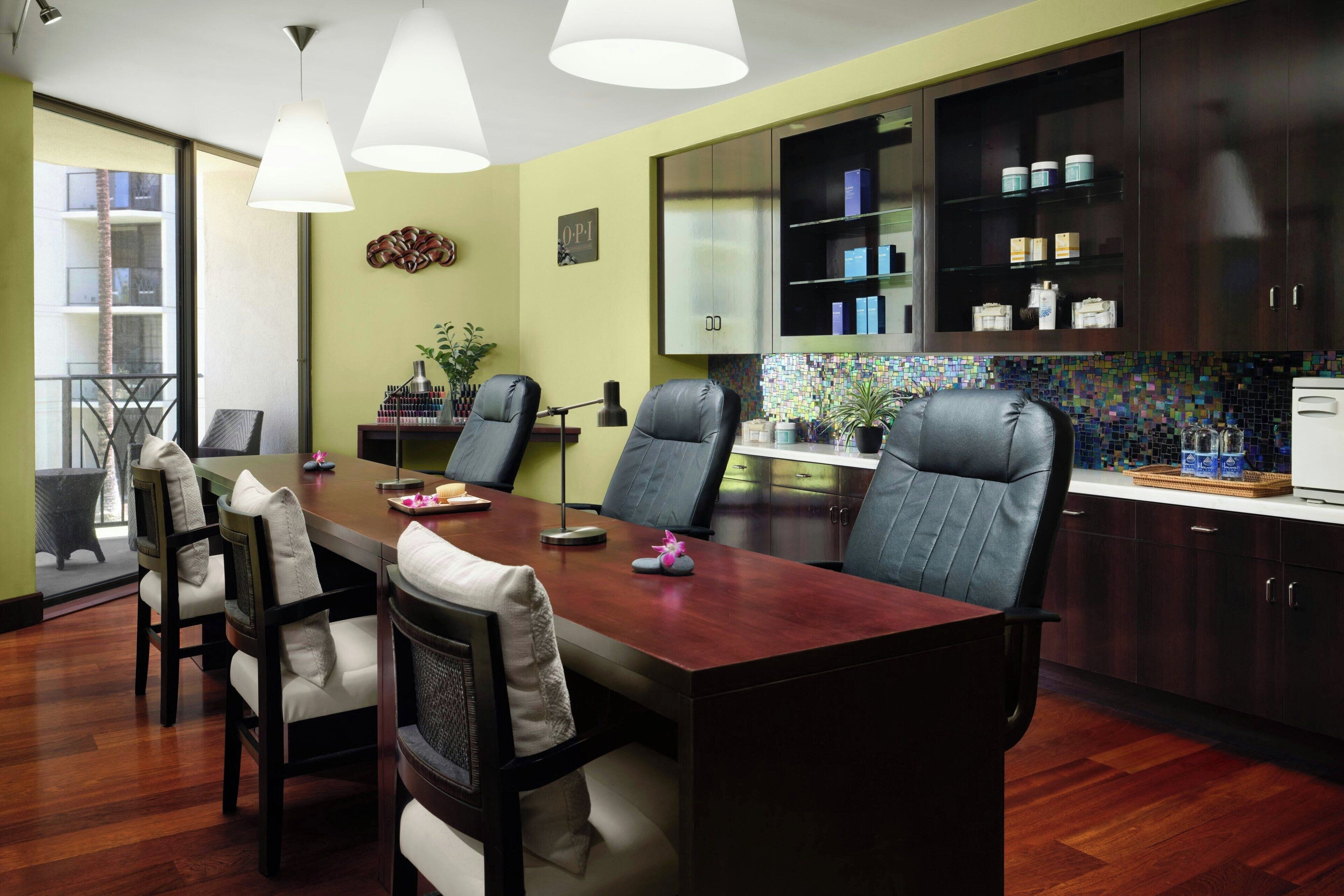 Un comedor moderno con una mesa de madera y sillas de cuero, una cocina con alacenas oscuras y un salpicadero colorido, y un amplio ventanal que proporciona luz natural.