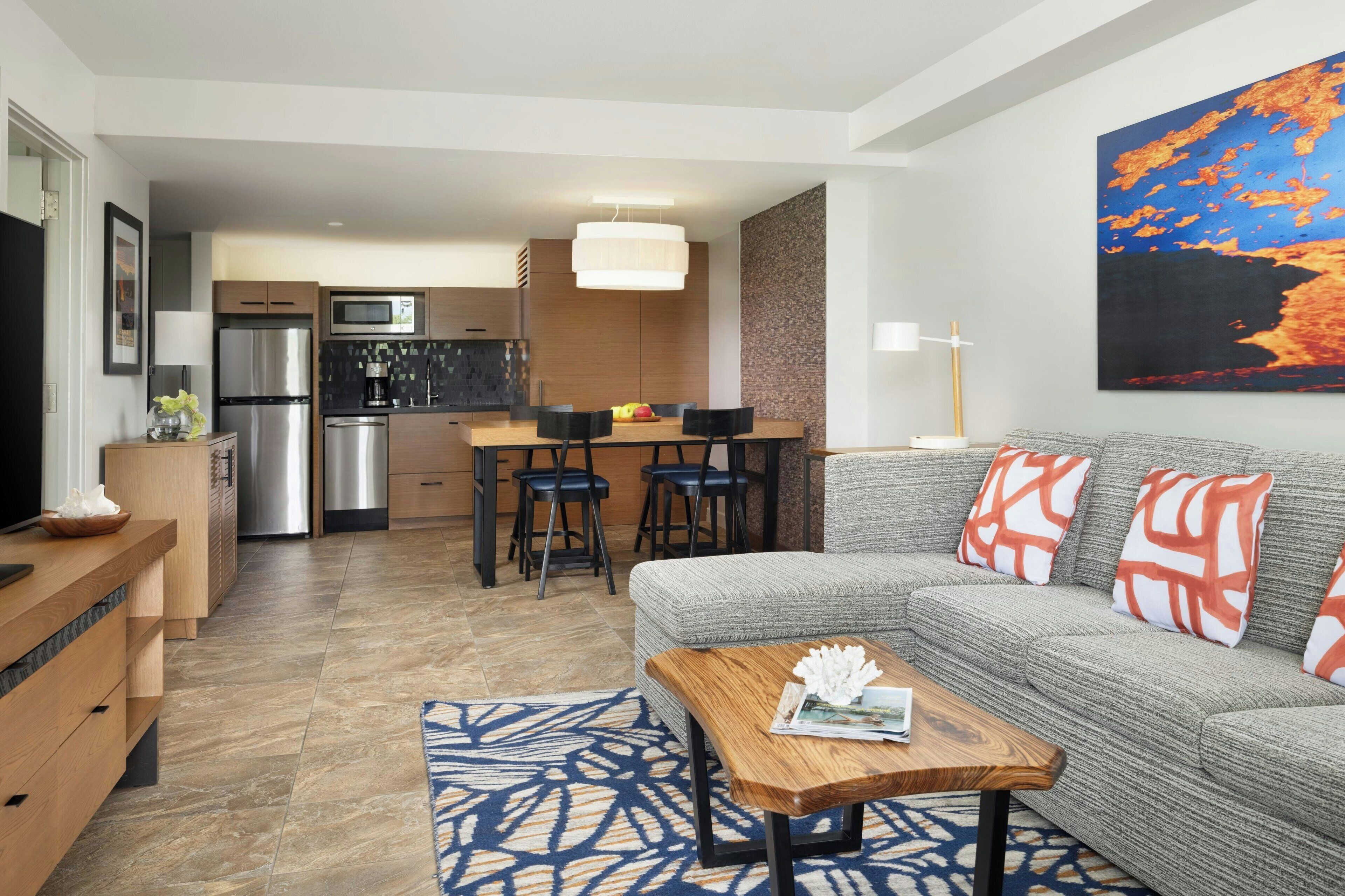 A modern living room with a grey sofa, wooden coffee table, and patterned rug.