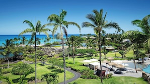 Een resort met een zwembad, palmbomen en uitzicht op de oceaan.