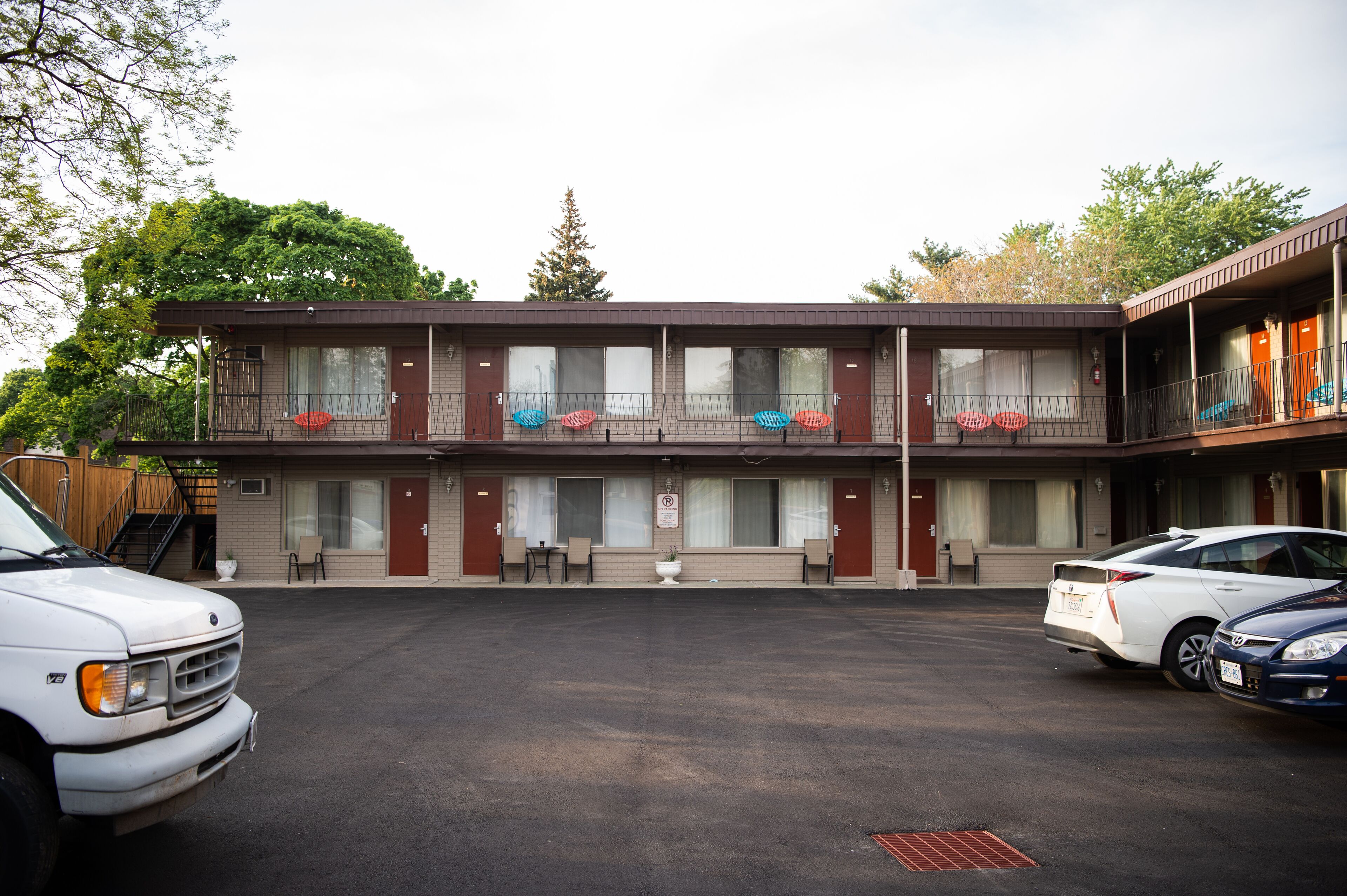 Un motel à deux étages, avec un parking et une voiture blanche garée devant.