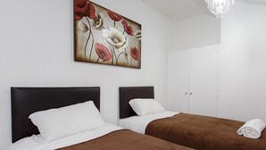 Quarto de hotel com duas camas, um quadro de flores na parede e um candelabro.