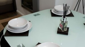 Uma mesa de jantar com pratos brancos, guardanapos pretos e um recipiente de vidro com palitos pretos.