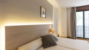 A hotel room with a large bed, a nightstand with a lamp, a framed picture on the wall, and a window with curtains. - Hotel Madrid (Pontevedra)