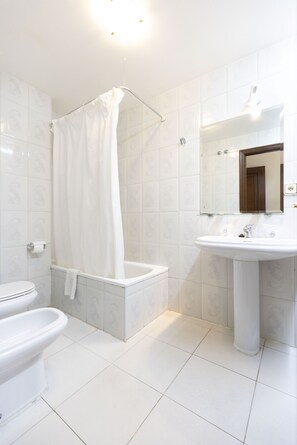 A modern bathroom with a white bathtub, a white sink, and a toilet. - Hotel Madrid (Pontevedra)