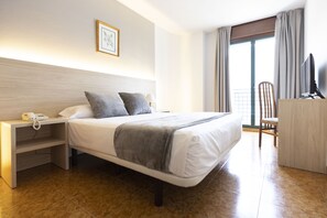 A hotel room with a bed, bedside table, a desk with a chair, a TV, and a window with curtains. - Hotel Madrid (Pontevedra)