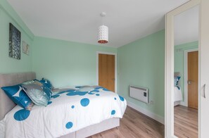 Ein Schlafzimmer mit Bett, einer Pendelleuchte, einer Tür und einer Heizung.
