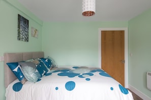 Quarto com uma cama, porta de madeira e luminária.
