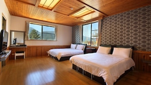 A room with two beds, wooden flooring, a desk, and large windows with a view of mountains. - Jia Maei B&B (Ren'ai)