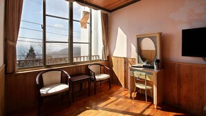 A room with wooden walls and a large window, a wooden desk with a chair, a small table with a chair, and a mounted TV. - Jia Maei B&B (Ren'ai)