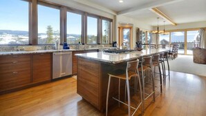 Une cuisine moderne dotée d’un grand îlot central, de meubles en bois et offrant une vue sur l’extérieur.