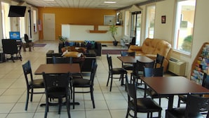 Un restaurante con mesas, sillas, un sofá y una televisión.