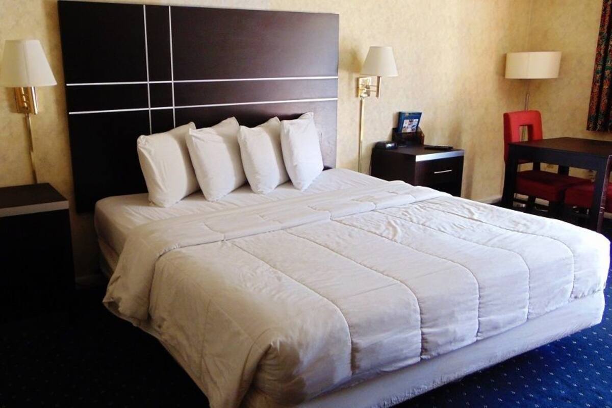A hotel room with a large bed, two bedside tables, a desk, and a chair.