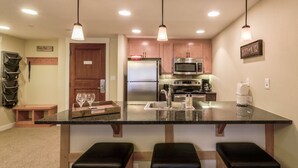 A kitchen with a central island, wooden cabinets, stainless steel appliances, and pendant lighting. - Founders Pointe 4457 2 Bedroom Holiday Home by Winter Park Lodging Company (Winter Park)