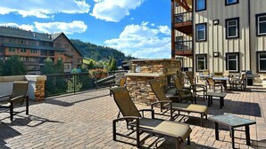 Un patio al aire libre con mobiliario y una chimenea de piedra, con vistas a un paisaje montañoso.