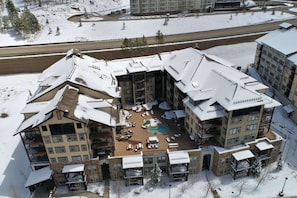 Un hôtel à plusieurs étages doté d’une piscine, d’un espace extérieur aménagé et d’une piste de ski en arrière-plan.