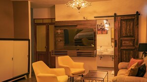 A modern living room with a sofa, two armchairs, a coffee table, a chandelier, a large mirror, and a wooden door. - Hotel Tepeyac (San Cristóbal de las Casas)