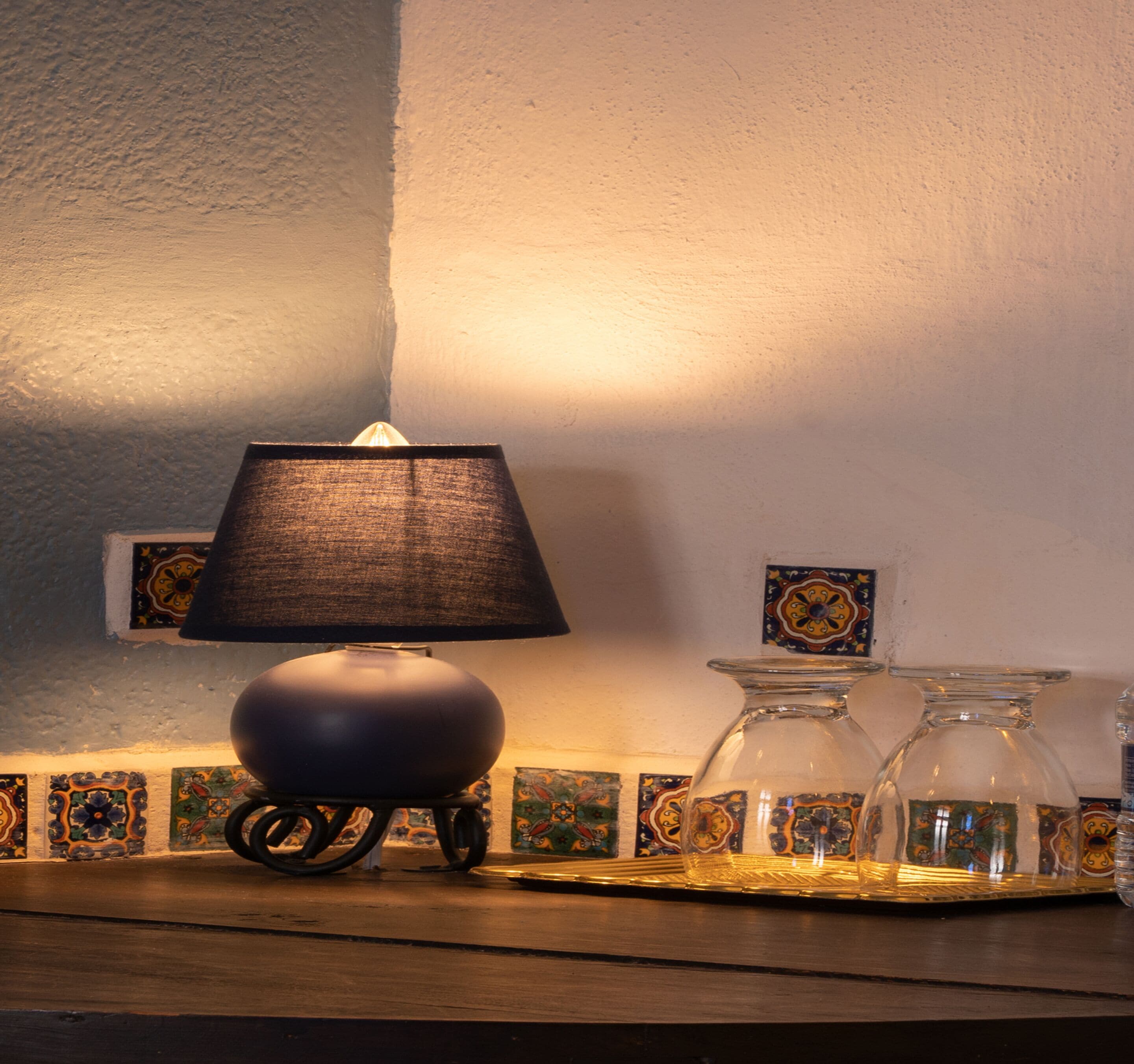 A table lamp on a wooden surface with a patterned tile border behind it.