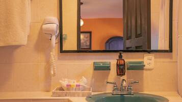 A bathroom with a sink, a hairdryer, and a mirror.