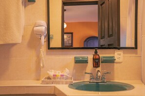 A bathroom with a sink, a hairdryer, and a mirror. - Hotel Tepeyac (San Cristóbal de las Casas)