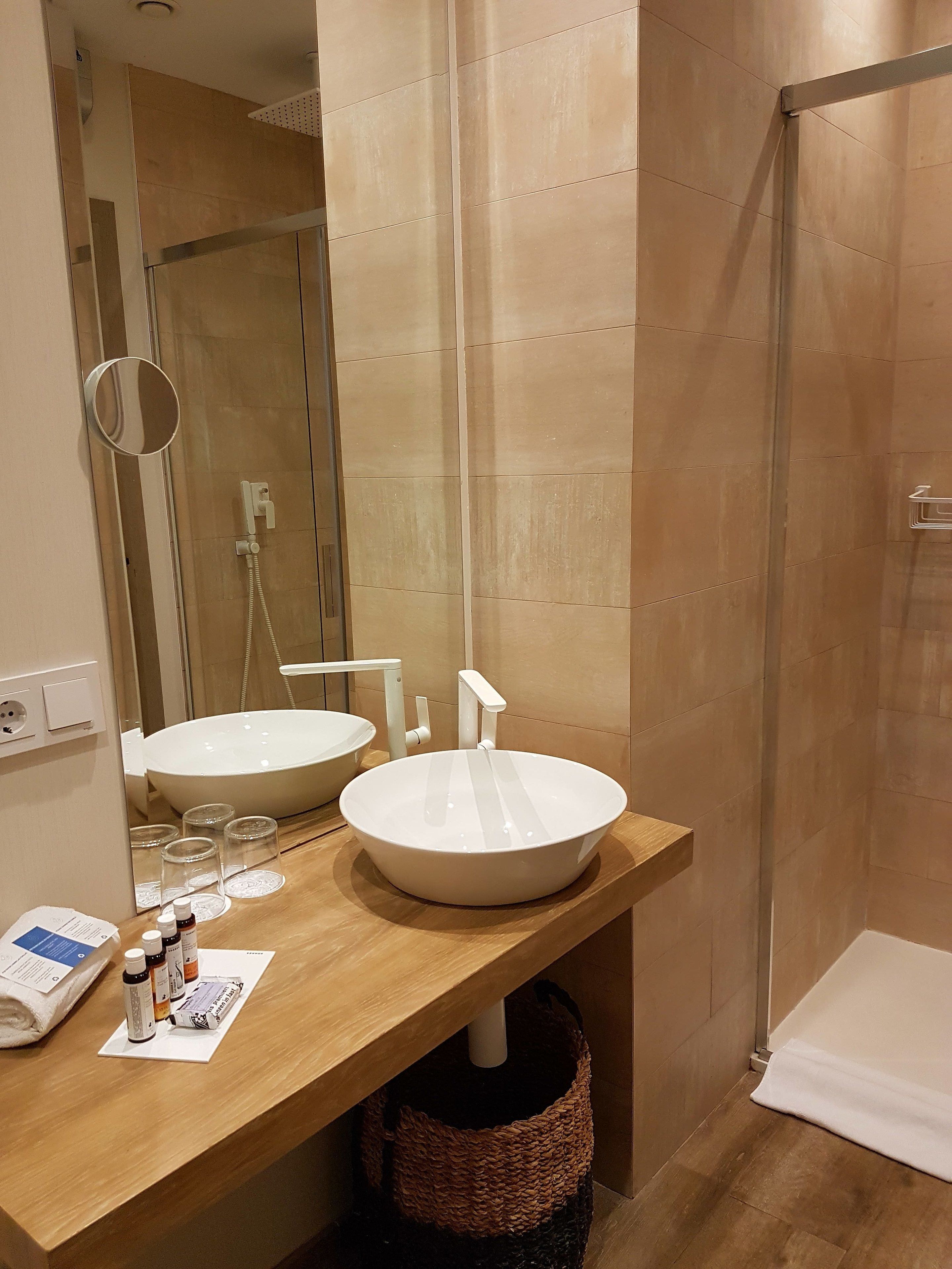 A bathroom with two sinks, a mirror, and a shower.