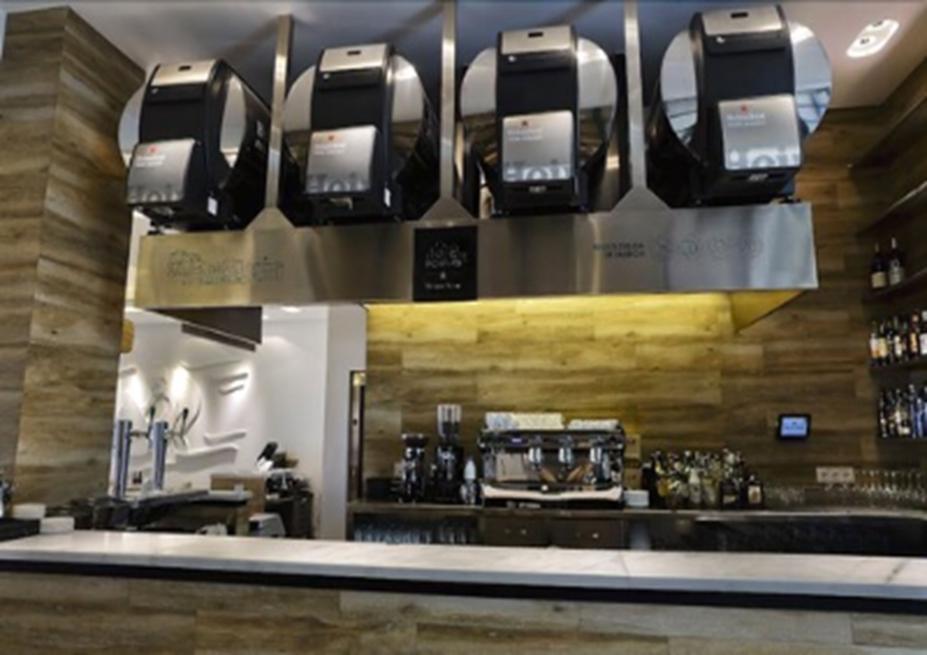 Un área de bar con varias máquinas de espresso, una cafetera y una exhibición de bebidas embotelladas.