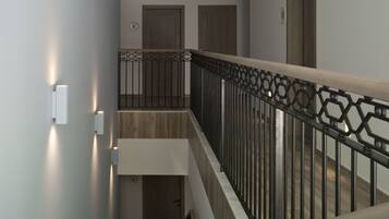 A modern interior with a staircase, wooden doors, and a geometric railing.