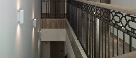 A modern interior with a staircase, wooden doors, and a geometric railing.