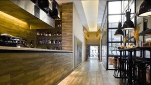 Zona de bar moderna con suelo de madera, taburetes y lámparas colgantes.