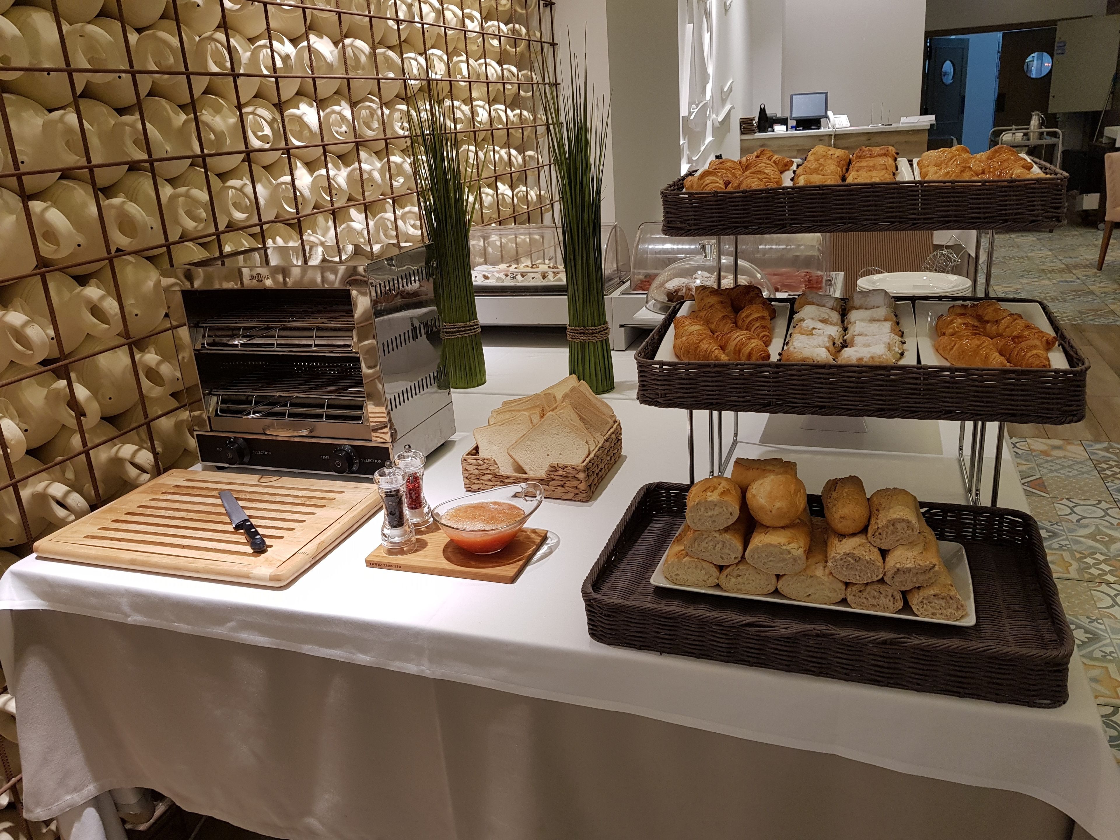 A buffet table with various food items, including bread, pastries, and a selection of condiments.